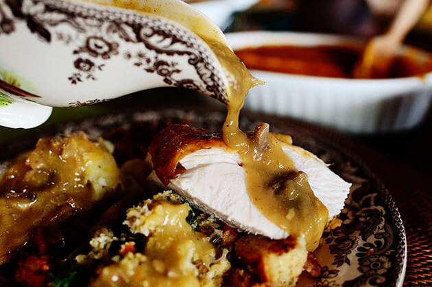 Gravy is poured over turkey and stuffing on a plate